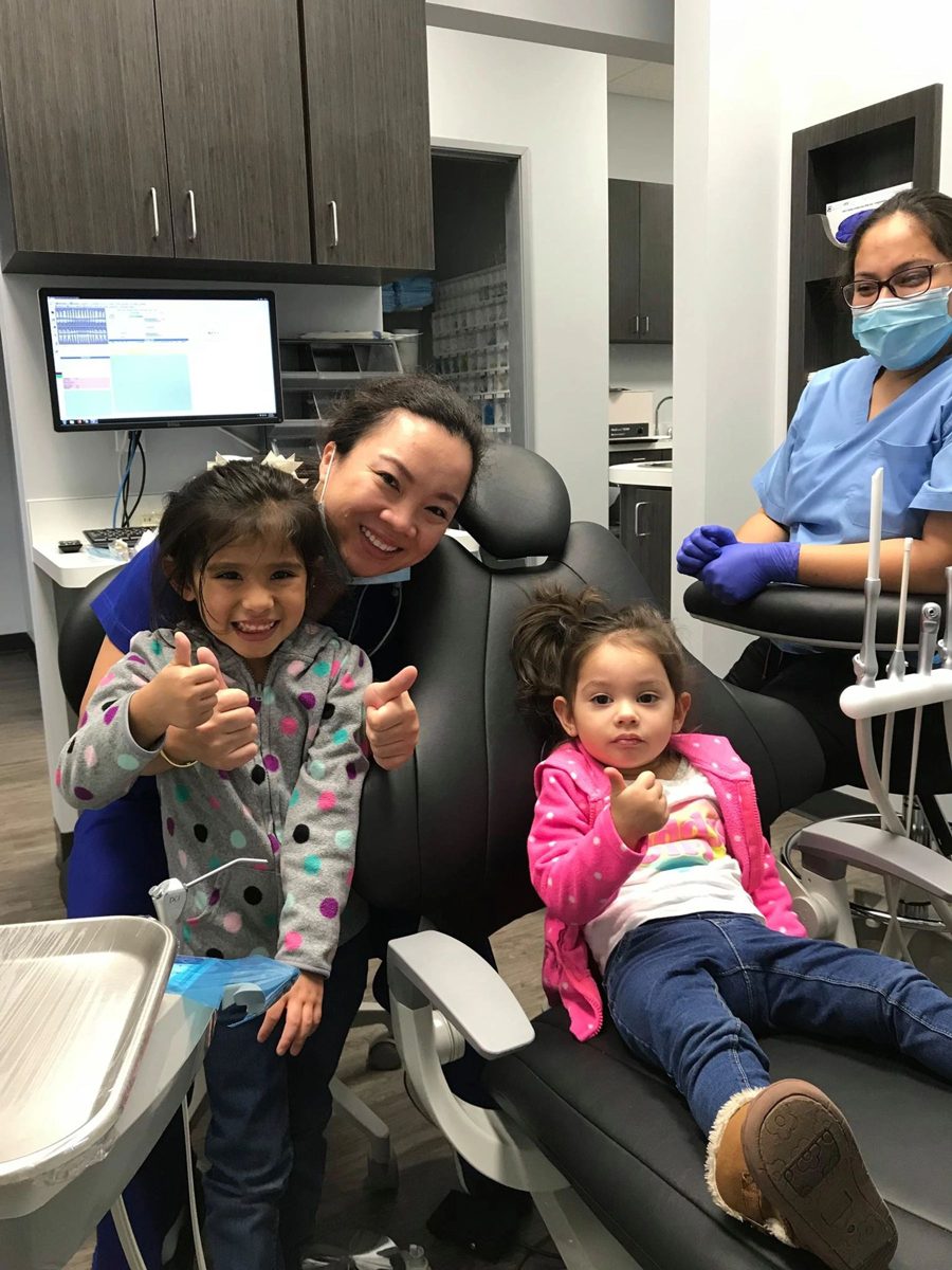 Two young patients giving a thumbs up in the dental chair