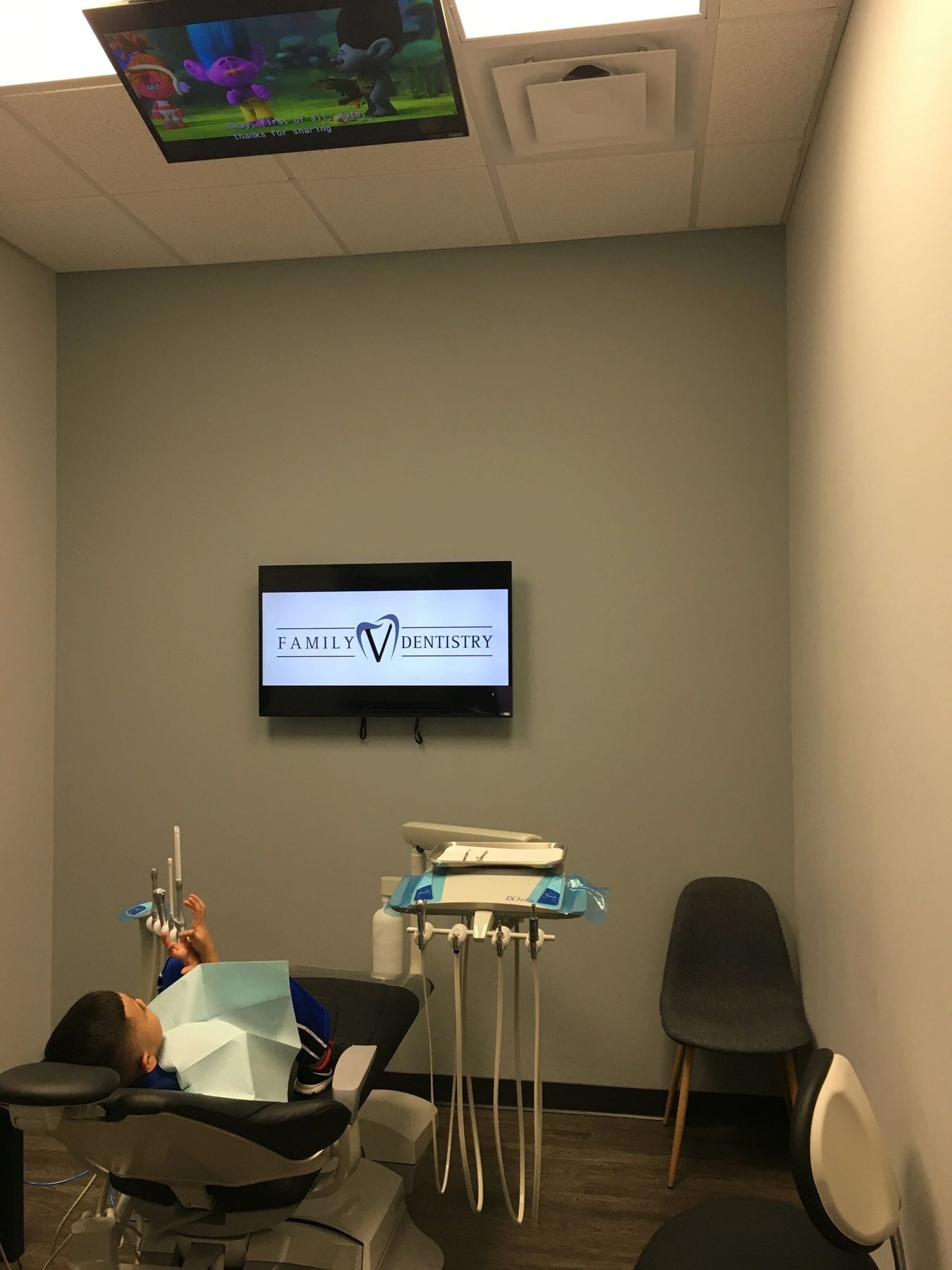 Treatment room with a ceiling-mounted TV above the dental chair